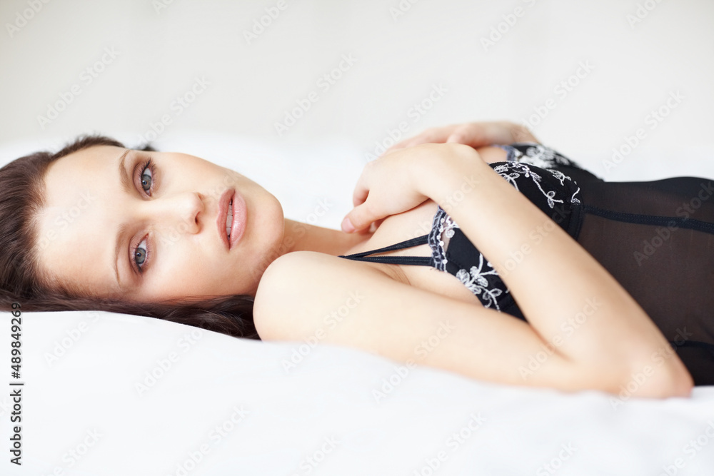 Obraz premium Sexy black lingerie woman lying on bed. Portrait of a cute young woman lying in black lingerie on bed.