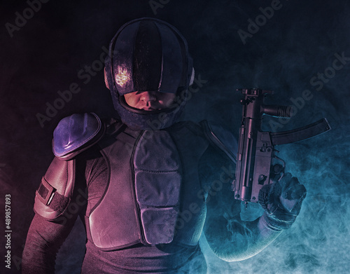 Cyberpunk concept, future world. Police officer cop in dark, halfman bionic cyborg or reloads gun, twitches cocking lever, Stands looks at camera in dark. Science fiction scene, fantasy, sci. photo