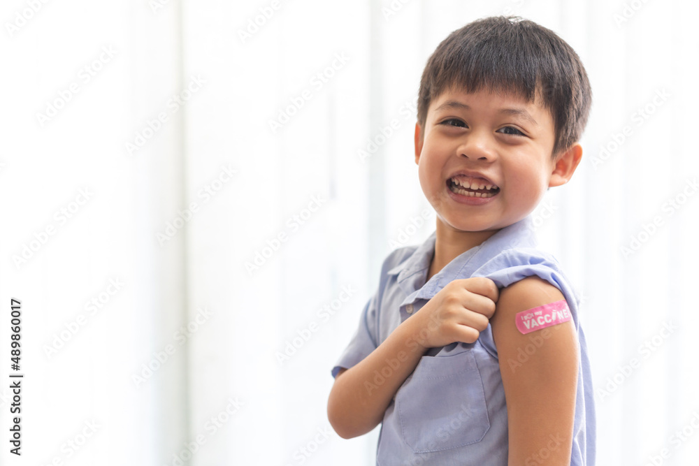 Portrait of happy smile vaccinated little asian kid boy children ages 5 to 11 years old posing show arm with medical plaster after Injection vaccine Covid-19 protection.coronavirus vaccination kid Portrait of happy smile vaccinated little asian kid boy children ages 5 to 11 years old posing show arm with medical plaster after Injection vaccine Covid-19 protection.coronavirus vaccination kid