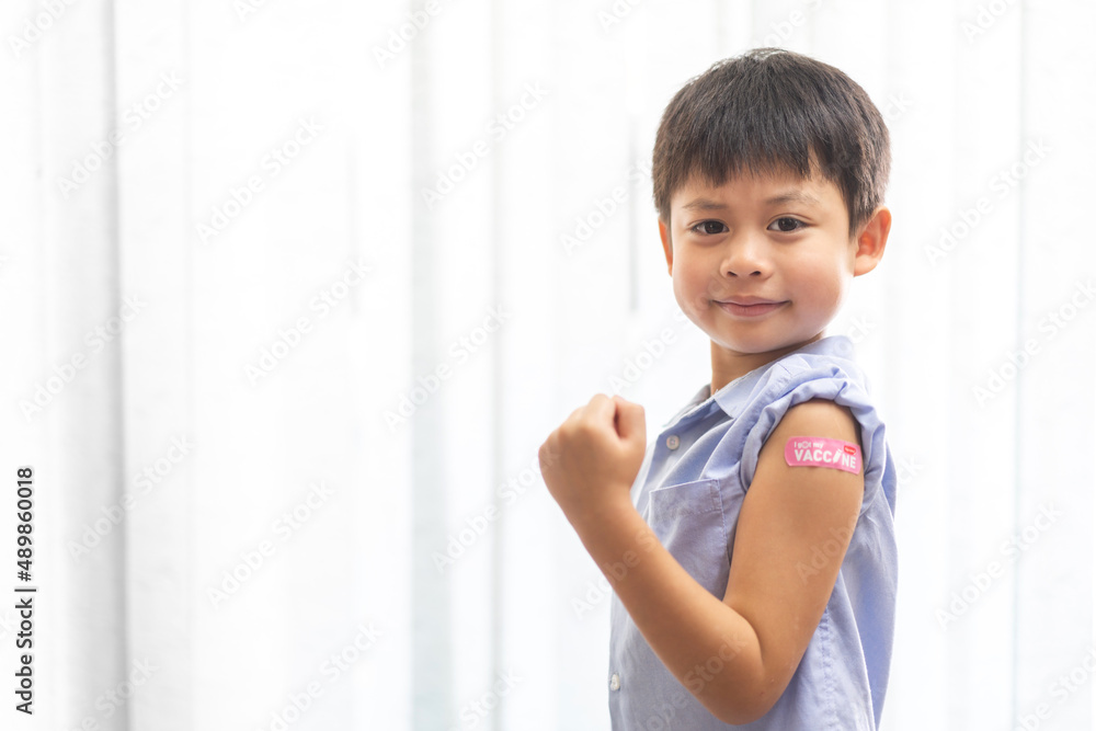 Portrait of happy smile vaccinated little asian kid boy children ages 5 to 11 years old posing show arm with medical plaster after Injection vaccine Covid-19 protection.coronavirus vaccination kid Portrait of happy smile vaccinated little asian kid boy children ages 5 to 11 years old posing show arm with medical plaster after Injection vaccine Covid-19 protection.coronavirus vaccination kid