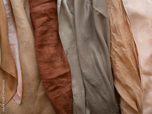 hand dyed clothes in warm natural tones hanging on a bright background - text space -
slow fashion concept 