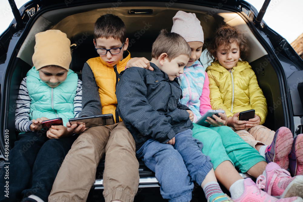 Children sitting on the car truck with smartphones