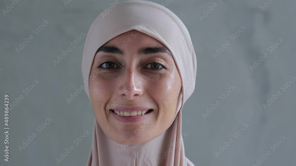 Cheerful cute Muslim young woman in hijab dress smiling and looking at the camera, pure happiness and joy Cheerful cute Muslim young woman in hijab dress smiling and looking at the camera, pure happiness and joy