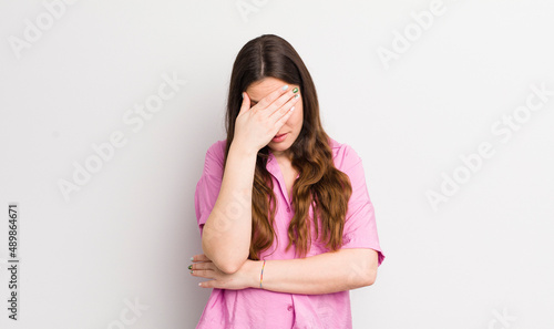 pretty caucasian woman looking stressed, ashamed or upset, with a headache, covering face with hand