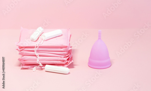 Menstrual cycle. Alternative means of hygiene and protection in critical days for women. Sanitary pads, tampons and silicone menstrual cup on pink background. Selective focus. Copy space
