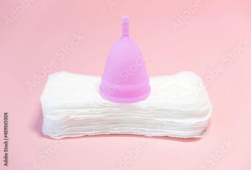 Menstrual cycle. Alternative means of hygiene and protection in critical days for women. Sanitary pads  or silicone menstrual cup on a pink background.   oncept   reuse  eco  safety. Selective focus. 
