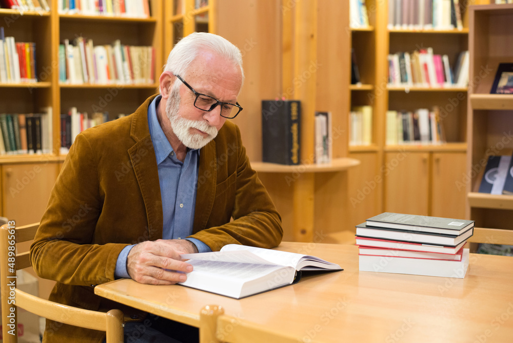 Senior man reading book in the library