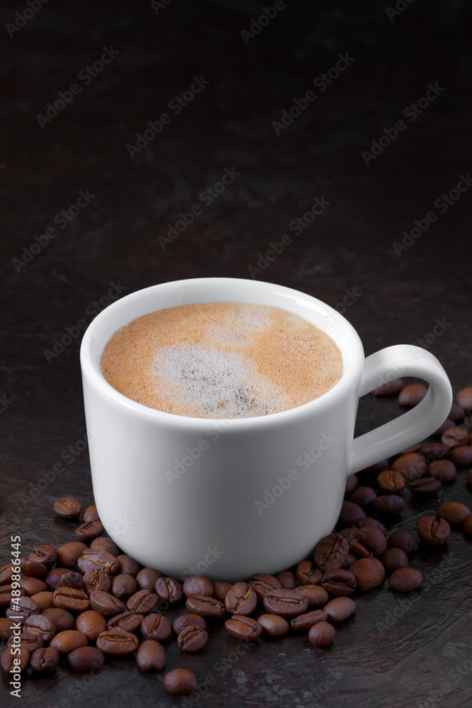 white cup of coffee with coffee beans on a dark background. vertical image white cup of coffee with coffee beans on a dark background. vertical image