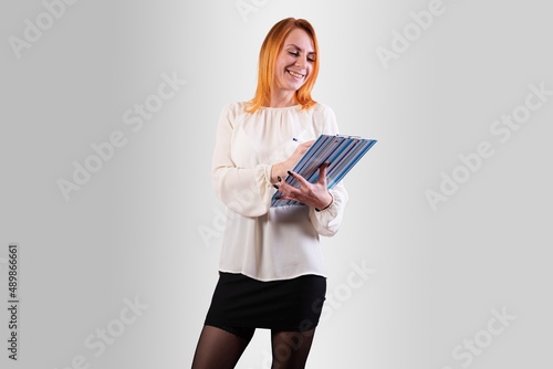 A girl in a business style, with a folder in her hands. On a gray background.