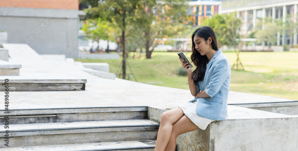 Beautiful business woman using mobile phone to play social media in the buildings at downtown. Smart female using cell phone chatting for business communication. Smartphone concept. Beautiful business woman using mobile phone to play social media in the buildings at downtown. Smart female using cell phone chatting for business communication. Smartphone concept.