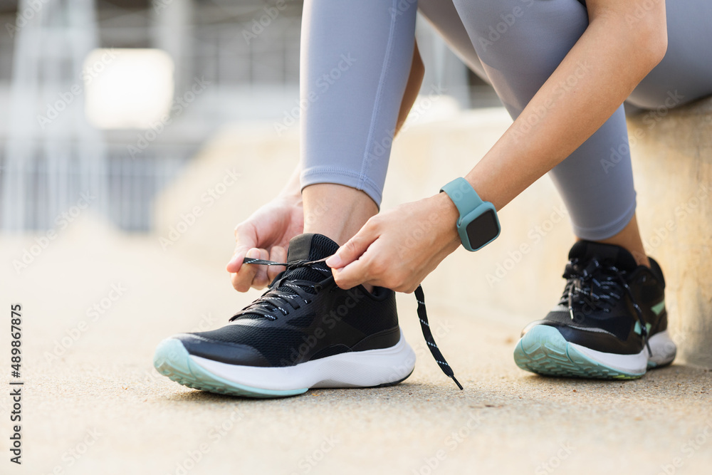 Close up hands woman runners tie shoelaces prepared to run outdoors. Young asian woman wearing sportswear running outdoor.Training athlete work out at outdoor concept.