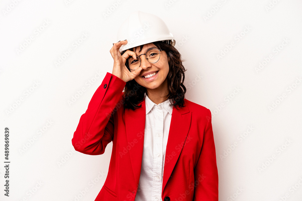 Young architect hispanic woman with helmet isolated on white background excited keeping ok gesture on eye. Young architect hispanic woman with helmet isolated on white background excited keeping ok gesture on eye.
