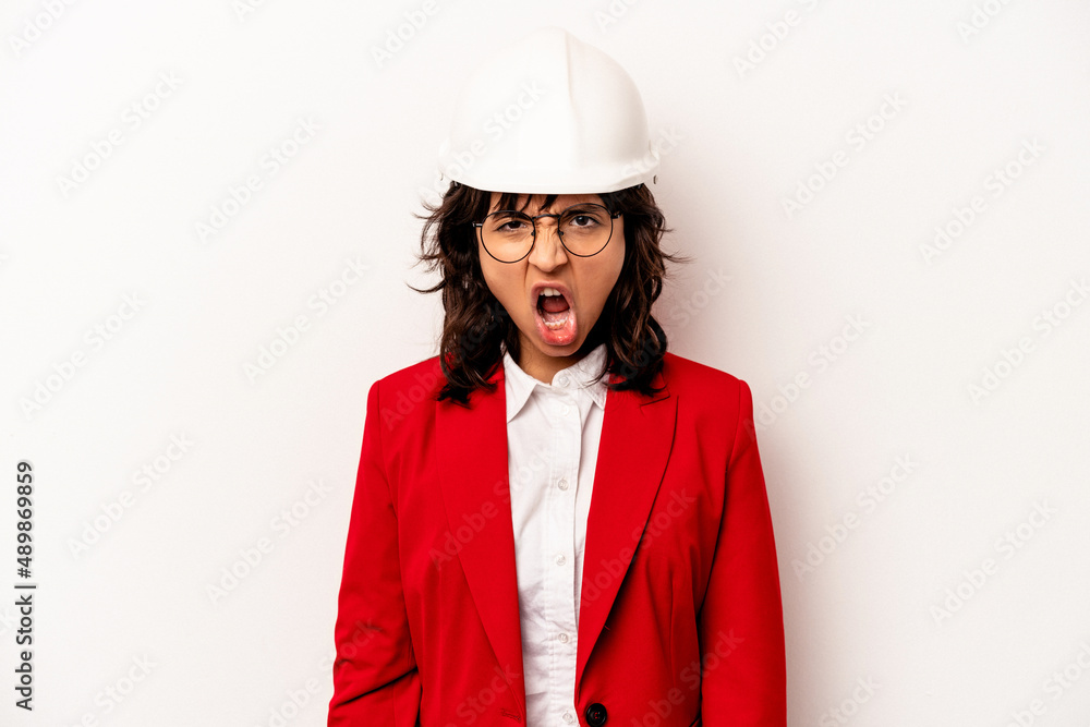 Young architect hispanic woman with helmet isolated on white background screaming very angry and aggressive. Young architect hispanic woman with helmet isolated on white background screaming very angry and aggressive.