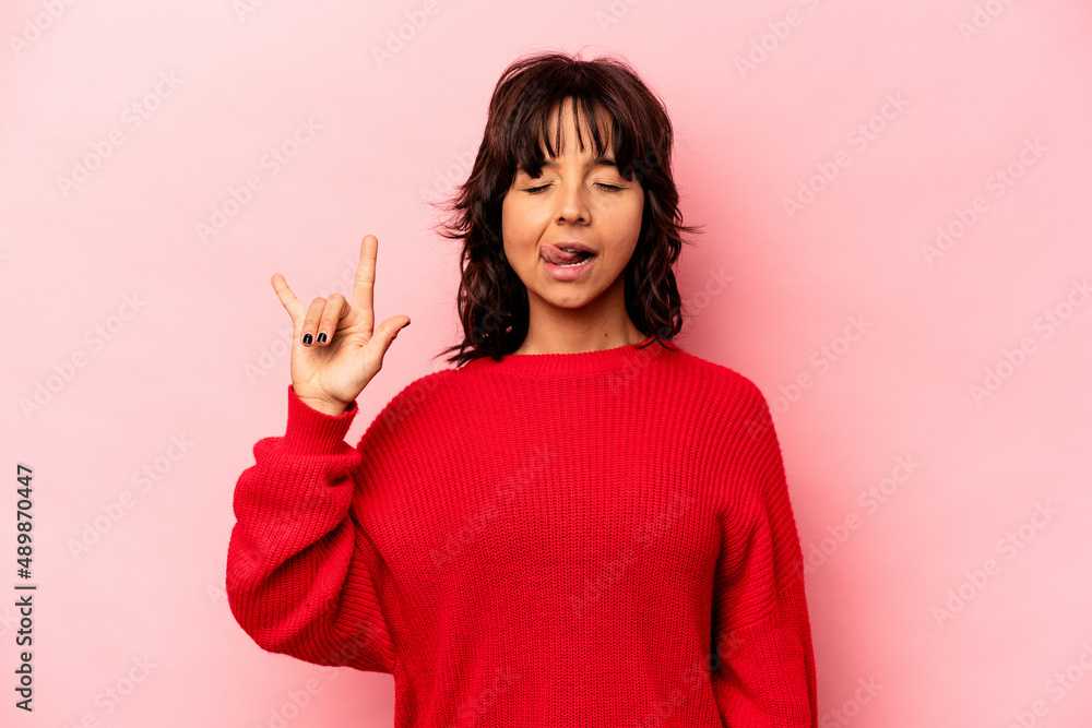 Young hispanic woman isolated on pink background showing rock gesture with fingers Young hispanic woman isolated on pink background showing rock gesture with fingers