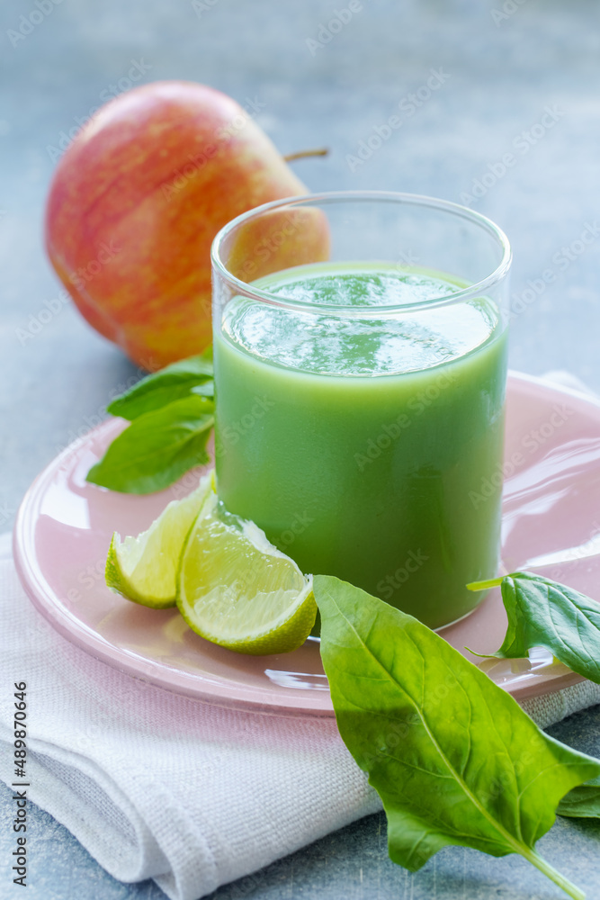 Fototapeta premium Green smoothie with spinach leaves, lime juice and apple in a glass, close-up
