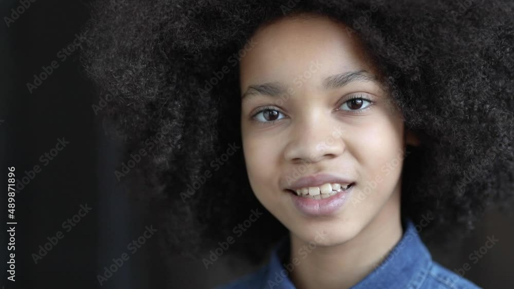 Dreamy smiling african american girl in denim shirt closeup indoors. Portrait. Dreamy smiling african american girl in denim shirt closeup indoors. Portrait.