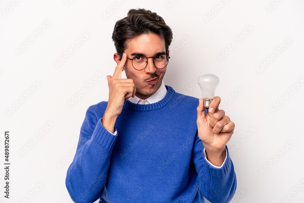 Young caucasian man holding a lightbulb isolated on white background pointing temple with finger, thinking, focused on a task. Young caucasian man holding a lightbulb isolated on white background pointing temple with finger, thinking, focused on a task.