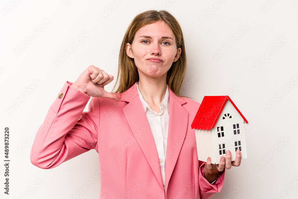 Young business English woman holding house toy isolated on white background feels proud and self confident, example to follow. Young business English woman holding house toy isolated on white background feels proud and self confident, example to follow.
