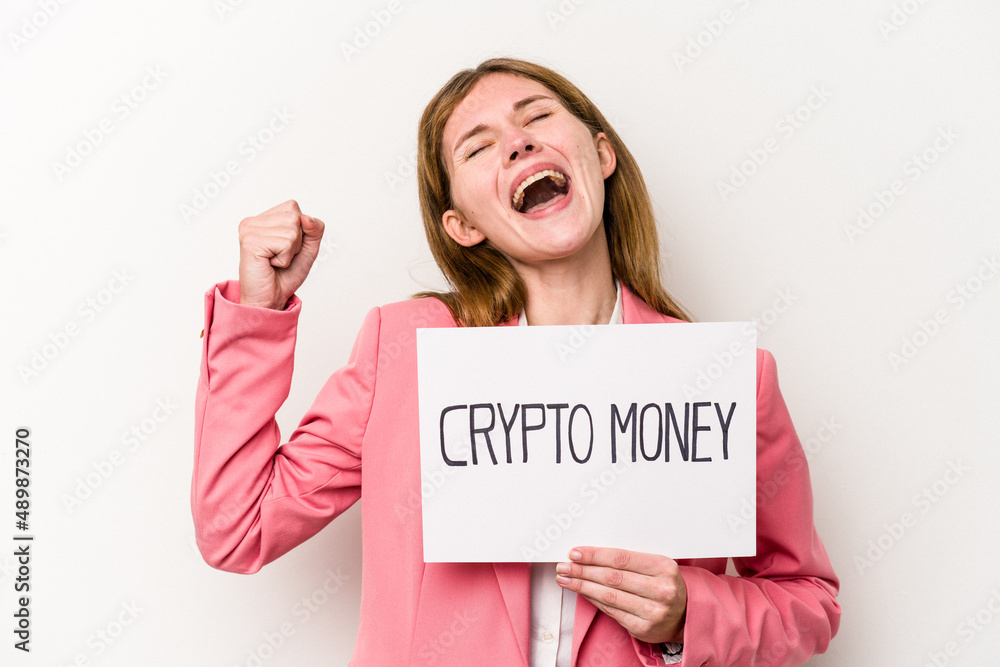 Young English business woman holding a crypto money placard isolated on white background raising fist after a victory, winner concept. Young English business woman holding a crypto money placard isolated on white background raising fist after a victory, winner concept.