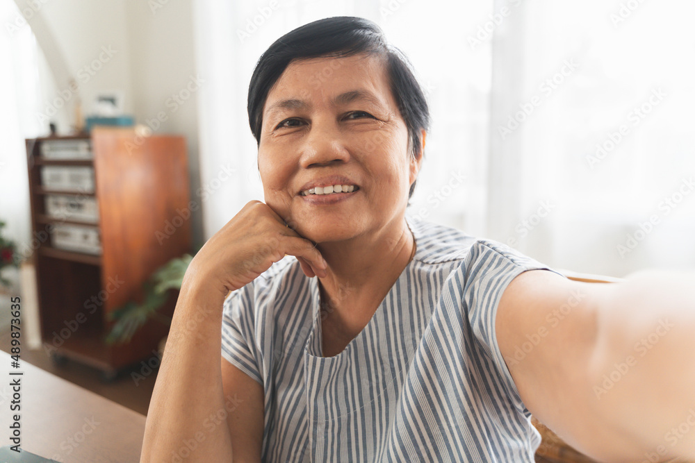 Smiling Asian senior woman using smartphone taking selfie. Smiling Asian senior woman using smartphone taking selfie.