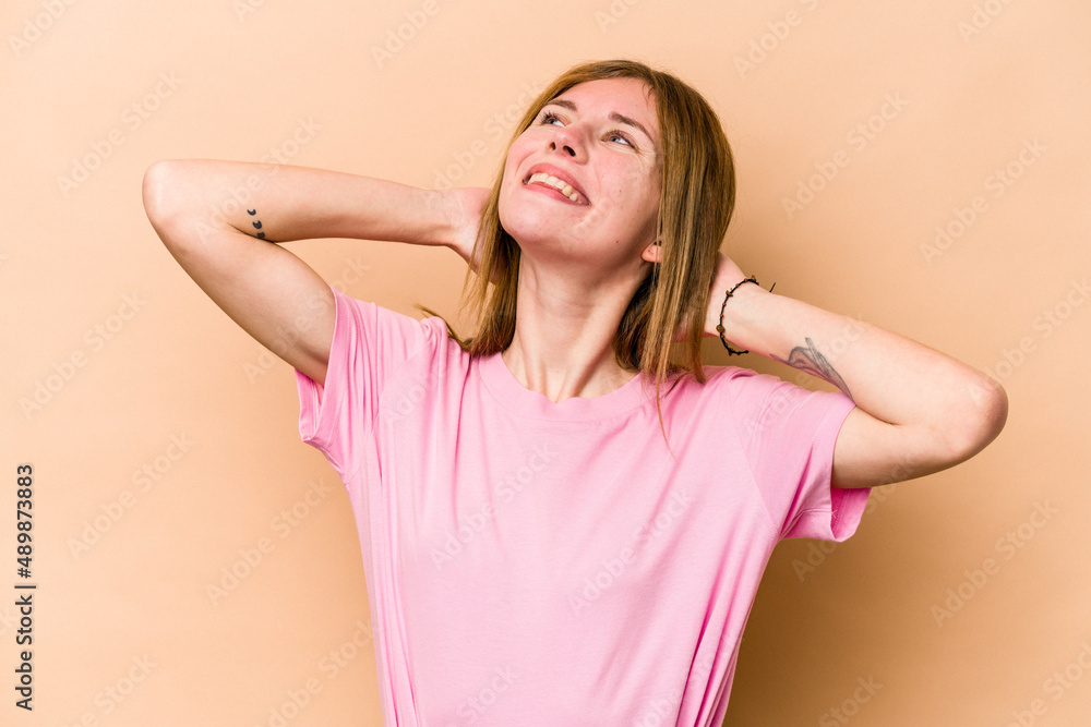 Young English woman isolated on beige background feeling confident, with hands behind the head. Young English woman isolated on beige background feeling confident, with hands behind the head.