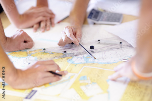 Locating the target is step one. Cropped shot of a group of unrecognizable male lifeguards finding co-ordinates on a map in their office. photo