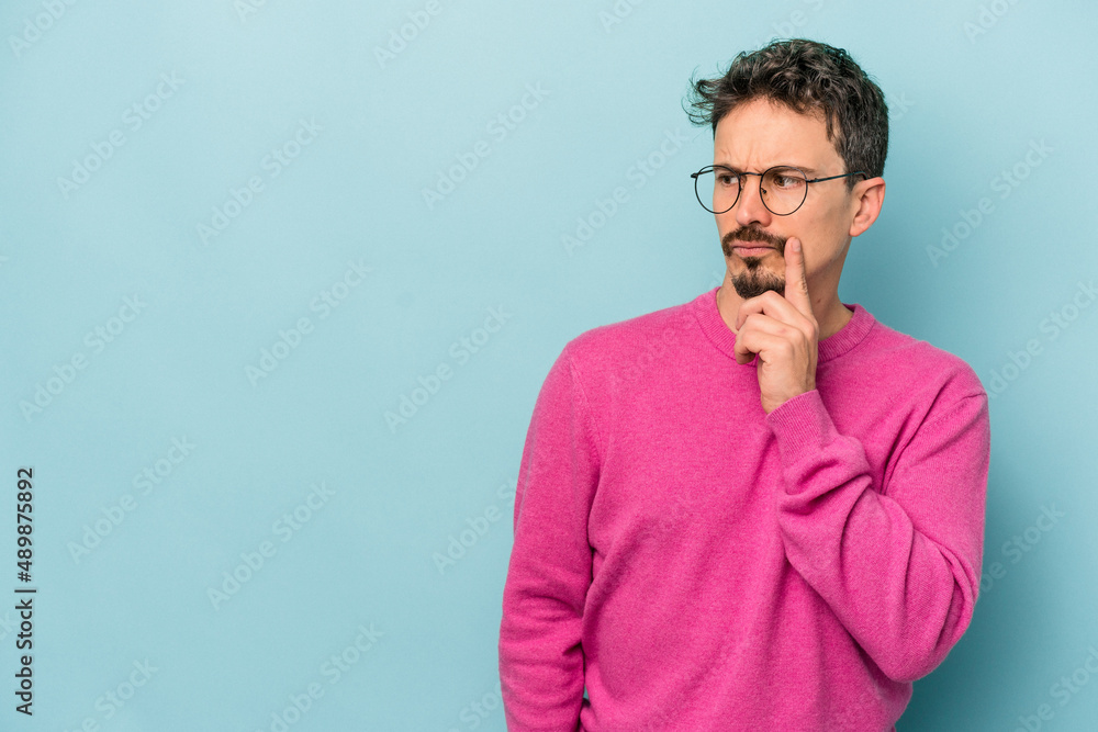 Young caucasian man isolated on blue background looking sideways with doubtful and skeptical expression. Young caucasian man isolated on blue background looking sideways with doubtful and skeptical expression.