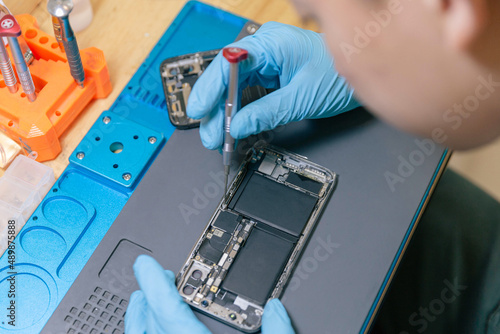 Phone repair concept a young electrical technician using a screwdriver to fasten the parts of an electronic device