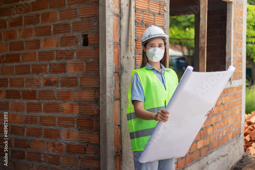 Wallpaper Mural engineer concept The female engineer wearing a white mask and helmet holding her proposal paper of the construction Torontodigital.ca