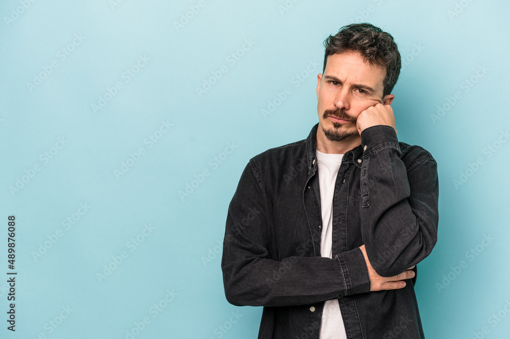 Young caucasian man isolated on blue background who feels sad and pensive, looking at copy space. Young caucasian man isolated on blue background who feels sad and pensive, looking at copy space.