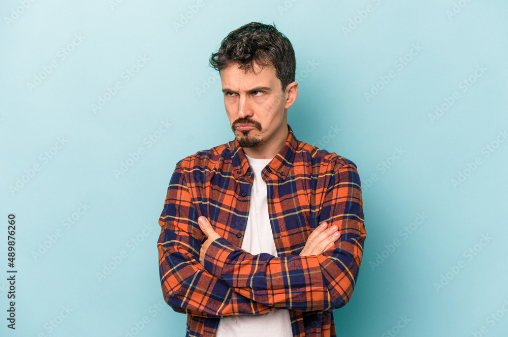 Young caucasian man isolated on blue background tired of a repetitive task. Young caucasian man isolated on blue background tired of a repetitive task.