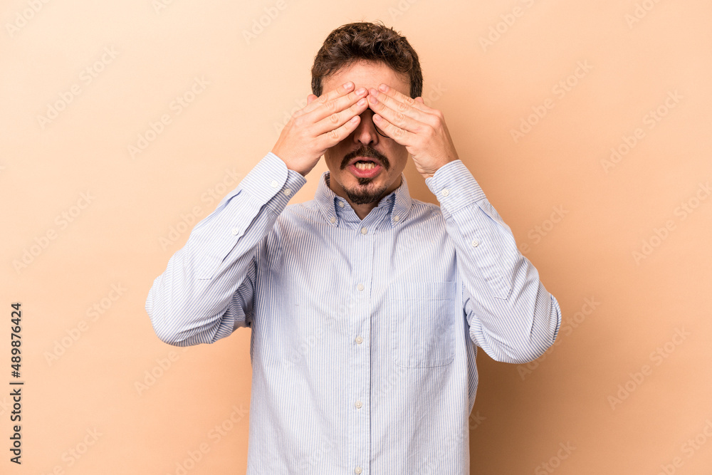 Young caucasian man isolated on beige background afraid covering eyes with hands. Young caucasian man isolated on beige background afraid covering eyes with hands.