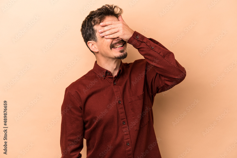 Young caucasian man isolated on beige background laughs joyfully keeping hands on head. Happiness concept. Young caucasian man isolated on beige background laughs joyfully keeping hands on head. Happiness concept.