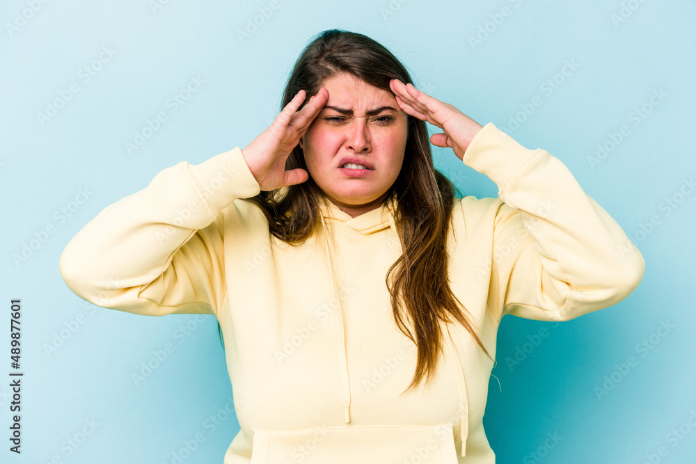 Young caucasian overweight woman isolated on blue background touching temples and having headache. Young caucasian overweight woman isolated on blue background touching temples and having headache.