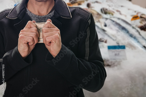 Man holding hands over money to protect his cash, safety of personal money savings