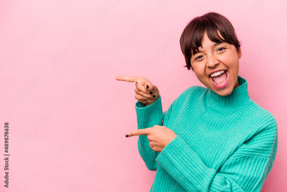 Young hispanic woman isolated on pink background excited pointing with forefingers away. Young hispanic woman isolated on pink background excited pointing with forefingers away.