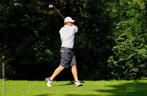 Golfer on a golf course, ready to tee off. Golfer with golf club hitting the ball for the perfect shot.