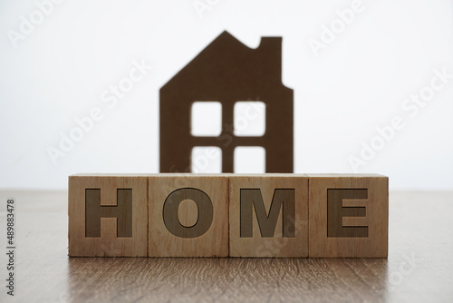 home wording on a wooden block with a house replica as background