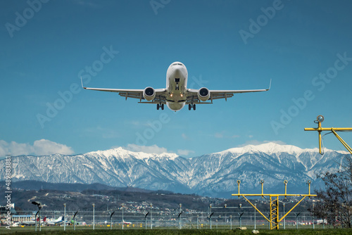 Takeoff of a white passenger aircraft against the backdrop of high picturesque mountains