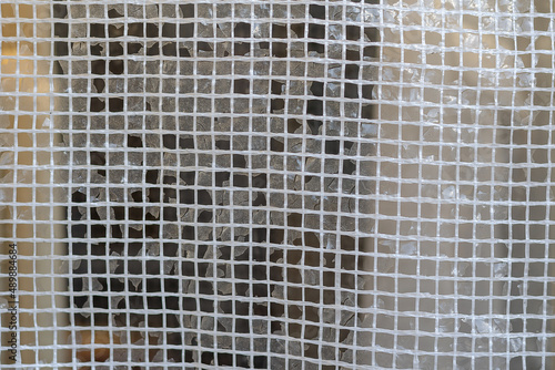 Texture of plastic mesh. Squares of white threads. Selective focus. Abstract background