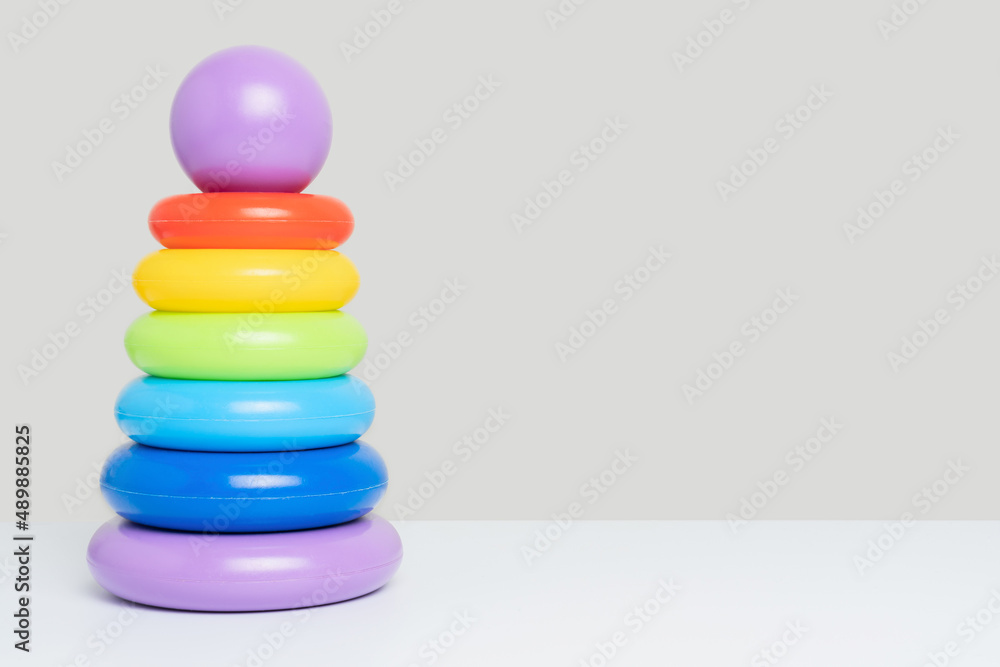 Children's educational toy pyramid of multicolored plastic rings on a gray background, copy space Children's educational toy pyramid of multicolored plastic rings on a gray background, copy space