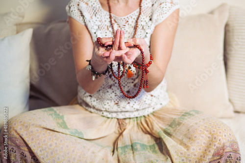 Woman at meditate place in lotus position using Mudra,  hand close up, strands of  beads used for keeping count during mantra meditations