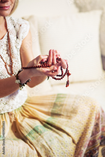 Woman at meditate place in lotus position using Mudra,  hand close up, strands of  beads used for keeping count during mantra meditations