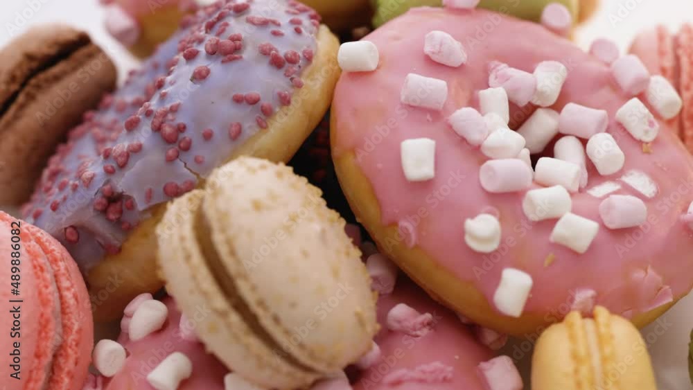 Macaroons and donuts rotate on a white background. Many multi-colored macarons donuts with different tastes, dessert. French macaroons Macaroons and donuts rotate on a white background. Many multi-colored macarons donuts with different tastes, dessert. French macaroons