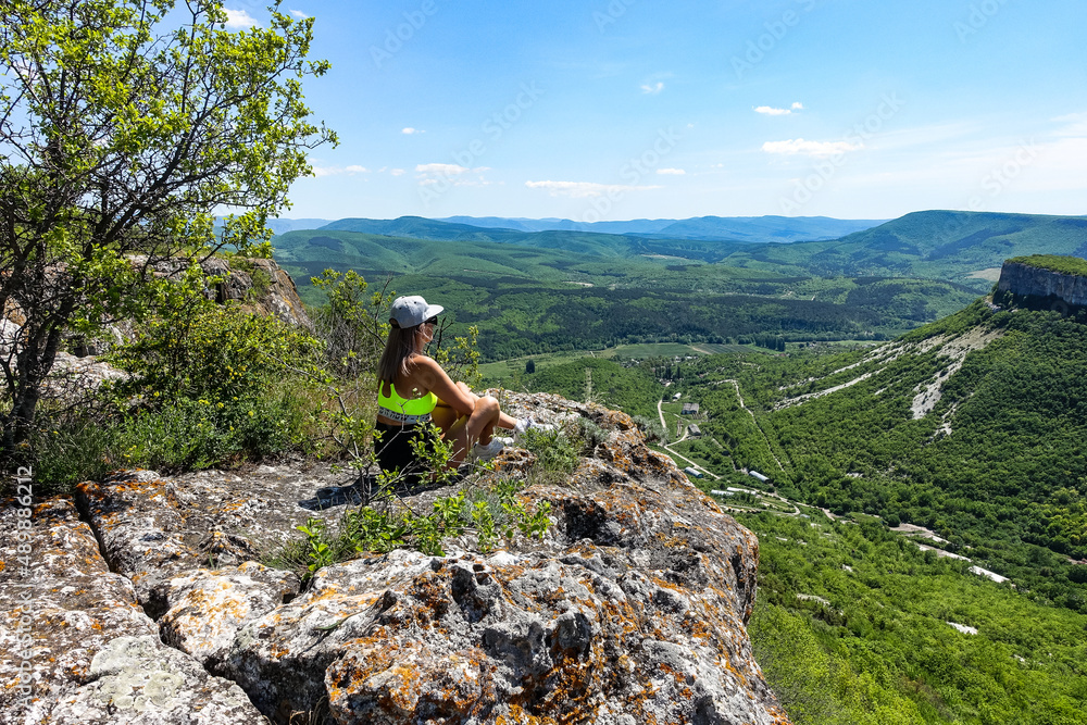 A girl on the background of a view of the Crimean mountains from the cave city of Tepe-Kermen. May 2021. Crimea. Russia.