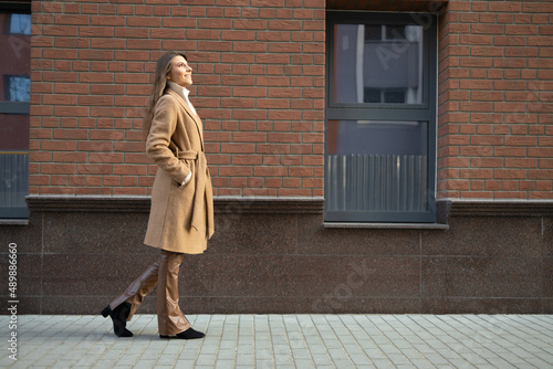 Wallpaper Mural Side view of beautiful woman in brown coat and leather pants near brick building Torontodigital.ca