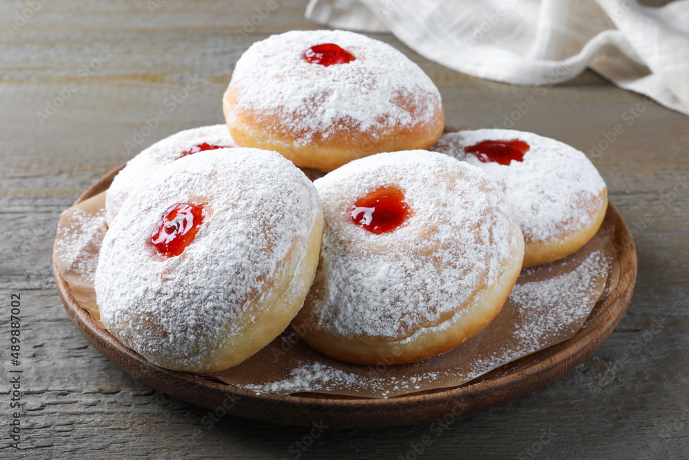 Delicious donuts with jelly and powdered sugar on wooden table