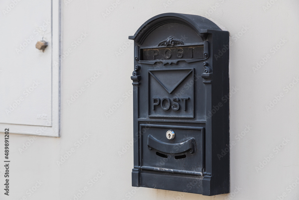 Close-up of a black metal mailbox on a white stone building