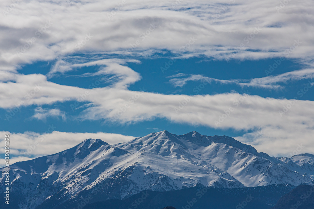 Panoramic view of high mountains with snow-capped peaks against a blue sky with clouds