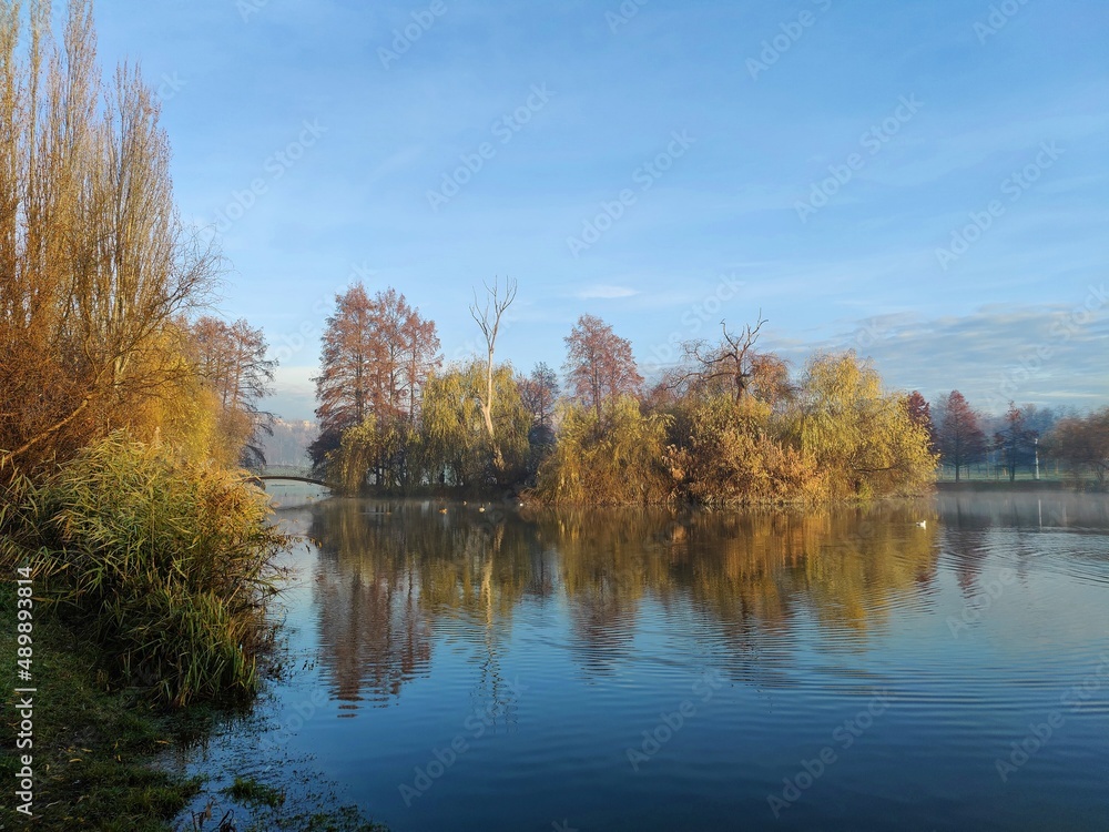 Autumn landscape with lake  - Autumn trees reflected in water. Sunny autumn day in the park